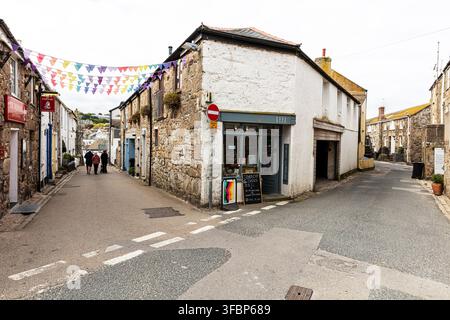 Traditional narrow streets and stone buildings in the historic centre of St Ives, Cornwall, England, with colourful bunting overhead and independent Stock Photo
