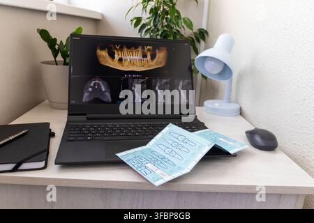 Laptop Displaying Dental 3D CBCT Tomography Software with Medical Packaging Strip on Keyboard Stock Photo