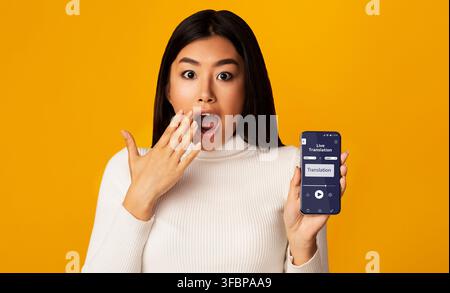 Surprised Asian Woman Holding Smartphone With Opened Voice Translation App On Screen Stock Photo