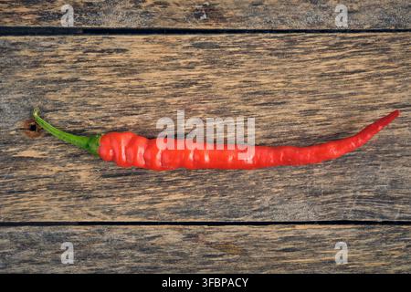 One long red chili pepper on rustic wooden table Stock Photo
