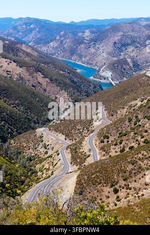 FREMONTS FORT, USA - JUNE 27 2026: A winding mountain road with switchbacks descends through dry foothills into a valley towards a large reservoir wit Stock Photo