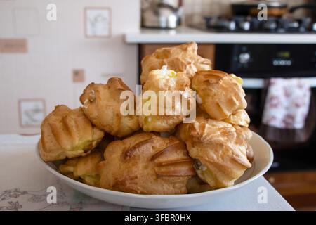 Homemade cream-filled profiteroles on a plate, close-up. Stock Photo