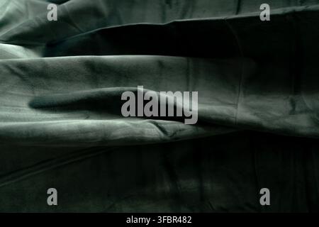 Close up of draped dark grey velvet cloth showing deep folds, soft texture, and shadows. Sharp details on the fabric surface. Stock Photo