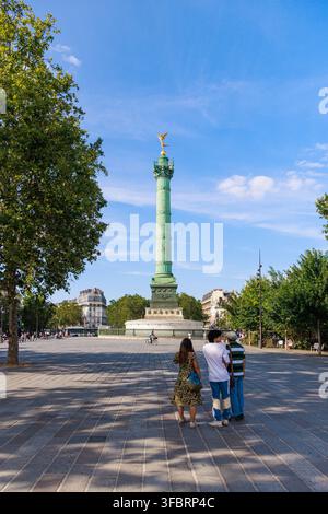 PARIS, FRANCE - JULY 20, 2026: Tourists look towards the July Column at Place de la Bastille in Paris. Three tourists stand on the paved square lookin Stock Photo