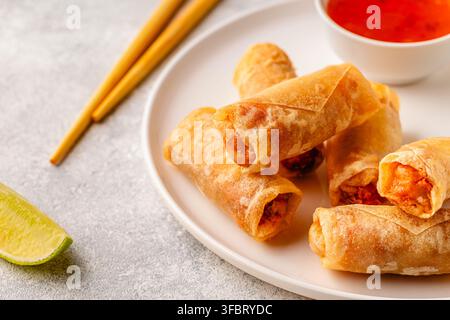 Fried spring rolls served with lime and sauce on a white plate Stock Photo