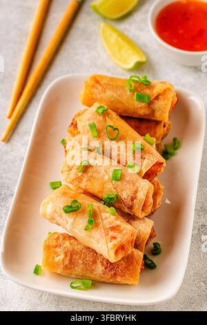Fried spring rolls served with lime and sauce on a white plate Stock Photo
