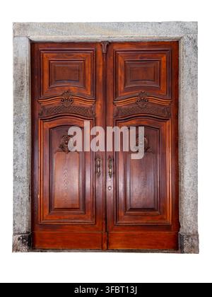 classic antique wooden entrance door with elegant hand-carved floral details, symmetrical brass handles, and a rustic grey stone frame - isolated on w Stock Photo