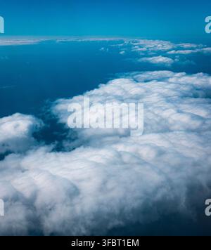Aerial view of a large white cloud formation above the deep blue ocean, photographed from high altitude. Stock Photo
