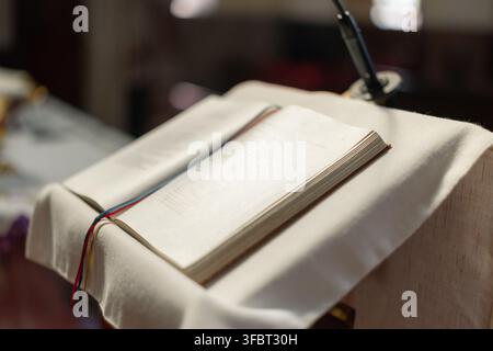 A religious ceremony takes place in a catholic church with an open holy bible on the altar. The community gathers in prayer and worship. Stock Photo