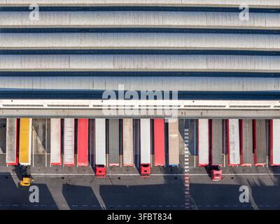 Aerial view of a logistics warehouse with multiple semi-truck trailers parked at loading docks in Settimo Torinese, Piedmont, Italy. Stock Photo