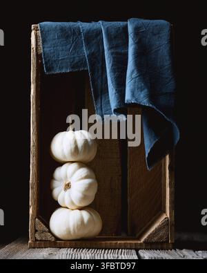 White decorative Baby Boo pumpkins in wooden box with blue napkin close up. Thanksgiving or Halloween food styling in cozy autumn setting Stock Photo