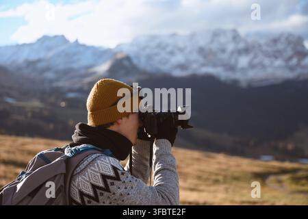Photographer capturing mountain scenery during autumn in the Dolomites. Outdoor travel and landscape photography with snow-covered peaks in the background Stock Photo