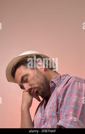 Worker with his respective protective helmet asleep on his right hand during working hours. Stock Photo