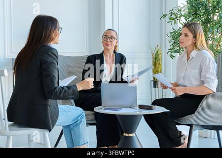 Group of diverse businesswomen discussing project documents during meeting in office Stock Photo