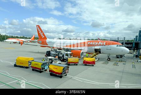 easyJet Airbus airliner on the apron at Manchester Airport with ground-service vehicles and baggage equipment. Stock Photo