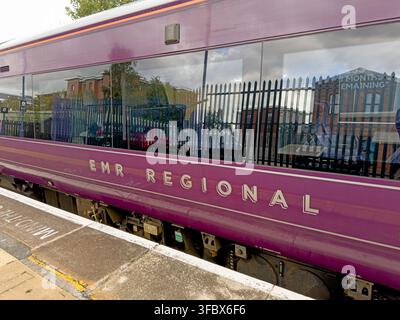 East Midlands Railway Regional train at Warrington Central station platform east bound, showing EMR purple livery and passenger carriage. Stock Photo