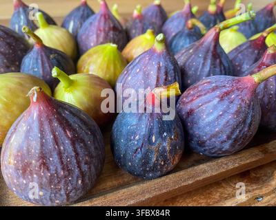Low angle close up shot of ripe purple and green figs arranged on a wooden tray with shallow depth of field. Concept for fresh harvest Stock Photo
