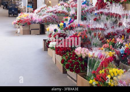 Artificial flowers bouquets displayed in cardboard boxes at a bazaar in Bukhara, Uzbekistan. Rows of wrapped roses and tulips create a colorful abunda Stock Photo