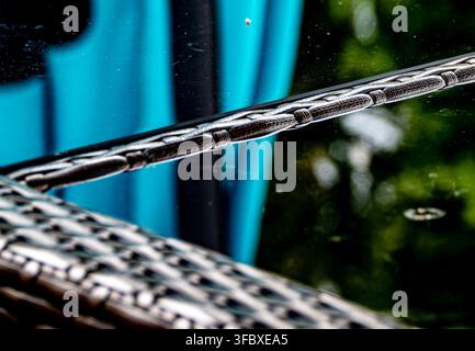 A piece of brown synthetic wicker furniture with a glossy textured weave reflected in a glass topped table. Stock Photo