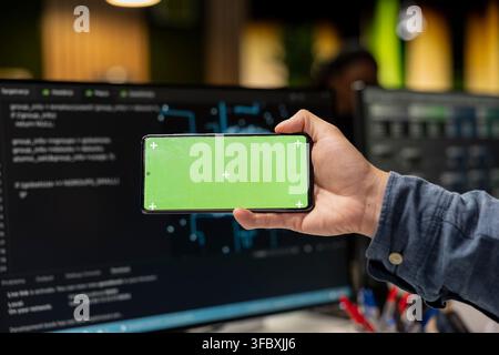 Close up of admin using isolated screen smartphone, debugging software issues and improving system stability. IT professional in tech startup office typing on touchscreen chroma key phone Stock Photo