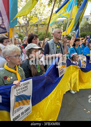 London, UK. 24 August 2026. Members of the Ukrainian community, including children, hold a large Ukrainian flag and placards during a gathering marking the 35th anniversary of Ukraine’s independence at the St Volodymyr Monument on Holland Park Avenue. Credit: Alexander Seale/Alamy Live News Stock Photo