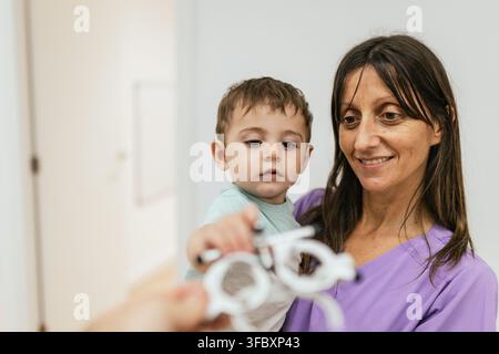 Optometrist holding trial frame in front of baby boy during eyesight testing Stock Photo