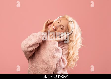 Happy Young Woman Enjoying Music With Headphones, Pink Background Stock Photo