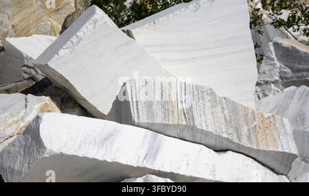 Large raw white marble blocks stacked in a quarry. Unpolished natural stone slabs with grey veining and rough textures. Industrial mining and construc Stock Photo