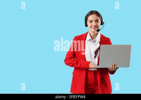 Customer service and technical support, smiling woman in headset holding laptop on blue background Stock Photo