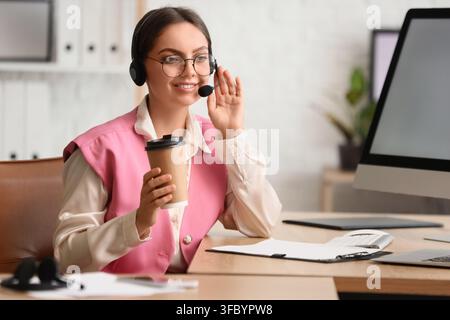 Customer service and call center support, smiling woman with headset and coffee working in a modern office Stock Photo