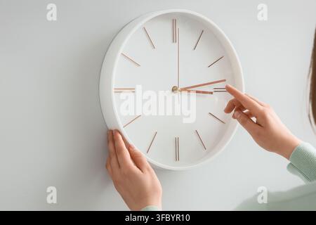 Woman setting time on wall clock at home, closeup. Daylight saving time concept Stock Photo