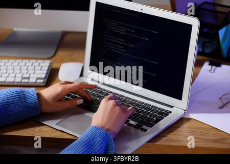 Female programmers hands working with laptop on table at office in evening, closeup Stock Photo