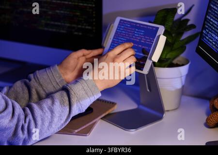 Female programmers hands testing code on tablet computer in office at night, closeup Stock Photo