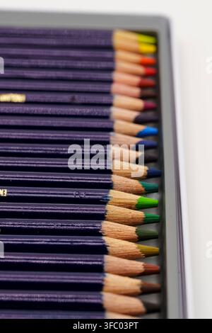 A neatly organized set of professional colored pencils displayed in a metal storage tin, showing sharpened tips in a rainbow spectrum of colors. The c Stock Photo