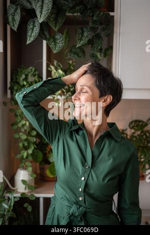 Happy senior woman in kitchen smiling at home kitchen. Quiet start to day, Self care, day dreaming Stock Photo