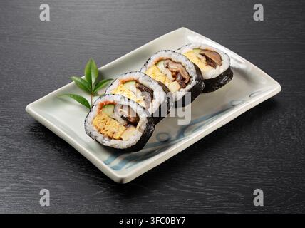 Japanese Futomaki Thick Sushi Rolls on Rectangular Ceramic Plate on Dark Wooden Table Stock Photo