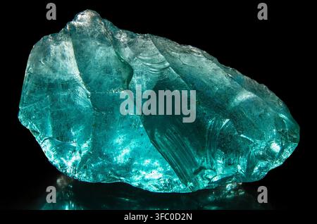 Turquoise piece of glass on a black background. Glass close-up. Stock Photo