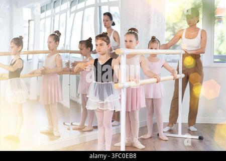 Girls in ballet class perform first position with correction of female mentor Stock Photo