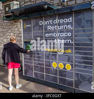 Mature fair haired white woman at the screen of an InPost parcel locker, one of thousands the Polish based company has in the UK and Europe. Stock Photo