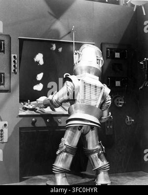 A 1954 black-and-white publicity still from the science fiction film "Tobor the Great," shows the robot Tobor operating a control panel with a screen displaying abstract forms. The character Tobor, constructed from metallic and segmented parts, is depicted from behind in what appears to be a laboratory or control room setting. Stock Photo