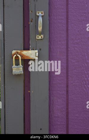Grey and purple painted Canexel wood plank cladded entrance door to a garden shed locked with heavy duty padlock, Quebec, Canada Stock Photo