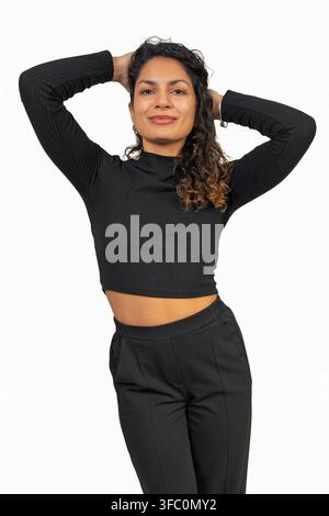 Young woman with curly hair wearing black casual clothes and smiling at camera Stock Photo