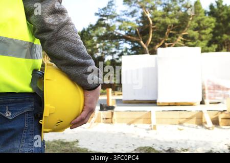 Construction professional holds safety helmet, surveys building site, checks progress of project, management, planning, construction business supervis Stock Photo