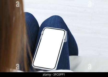 Rear view of young woman looking at phone with white blank screen mockup. Lifestyle concept with digital technology Stock Photo