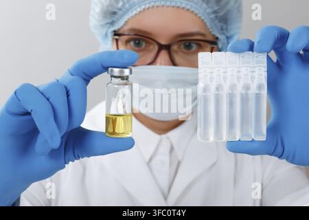 In the laboratory, a female scientist wearing protective gloves and glasses holds tubes with samples of medical tests Stock Photo