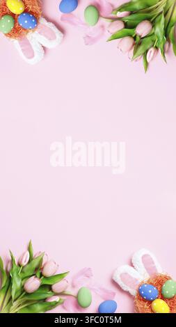Easter eggs, tulips, bunny ears on a pink background. Greeting card with copy space flat lay Stock Photo