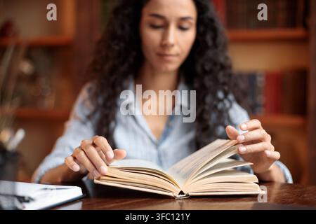 Young lady reading book sitting at desk Stock Photo