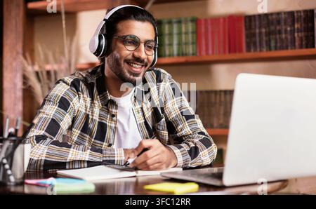 Positive Indian Student Guy At Laptop Learning Online At Home Stock Photo