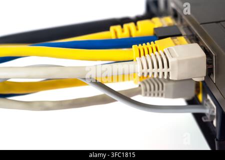 Cables connect to a router with various colors including yellow, blue, and gray in a simple workspace. Stock Photo