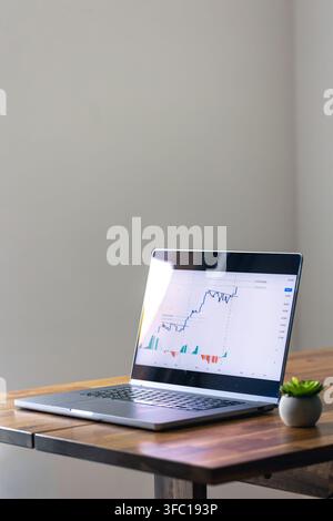 Laptop displaying financial chart on wooden table. Online trading with copy space. Stock Photo